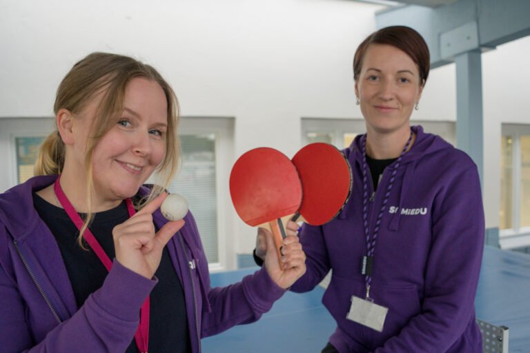 Kaksi henkilöstömme edustajaa hymyilee pidellen käsissään pingosmailoja niin, että niistä muodostuu sydän.