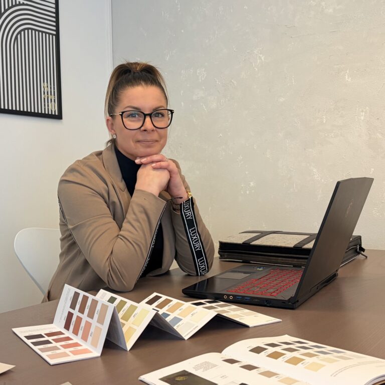 Sisustussuunnittelija työpöydän ääressä, pöydällä on värikarttoja.
