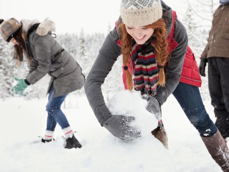 Ihmiset ovat ulkona talvella ja pyörittävät isoja lumipalloja