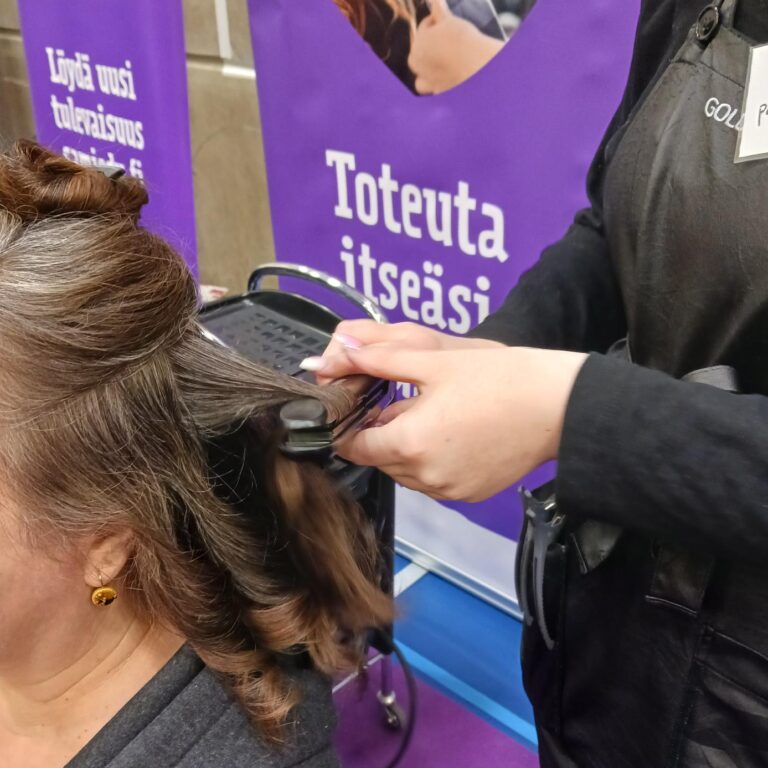 Opiskelija kihartaa asiakkaan hiuksia.