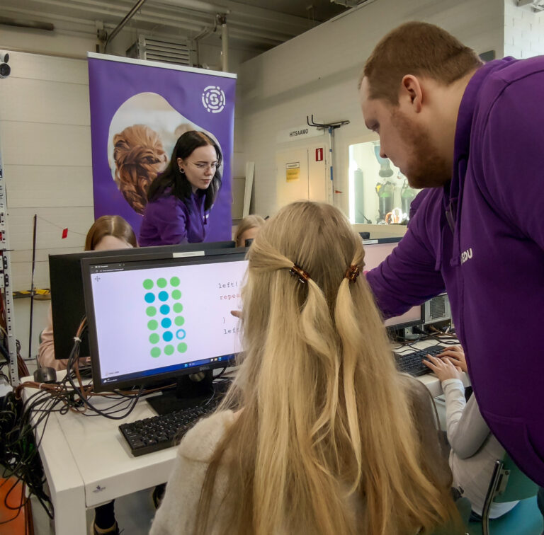 Opiskelijat ohjaavat oppilaita ohjelmointitehtävässä