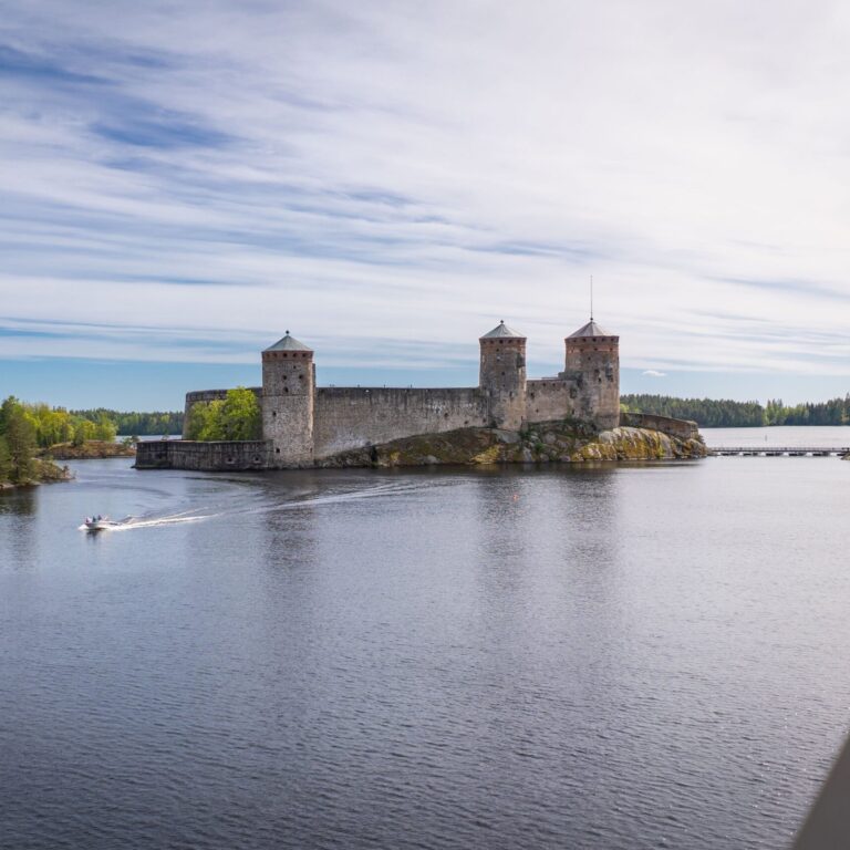 Kuvassa Olavinlinna järvimaisemassa. Kuvassa vasemmalla kulkee moottorivene.